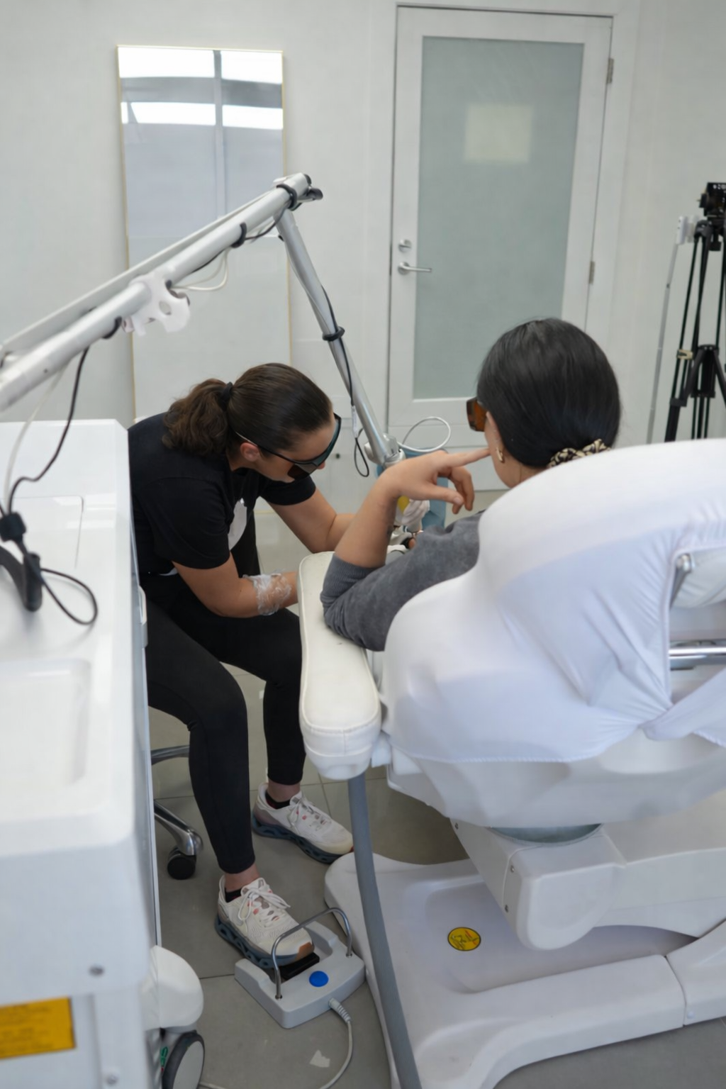Person administering treatment to a patient's arm in a medical setting, using a laser.