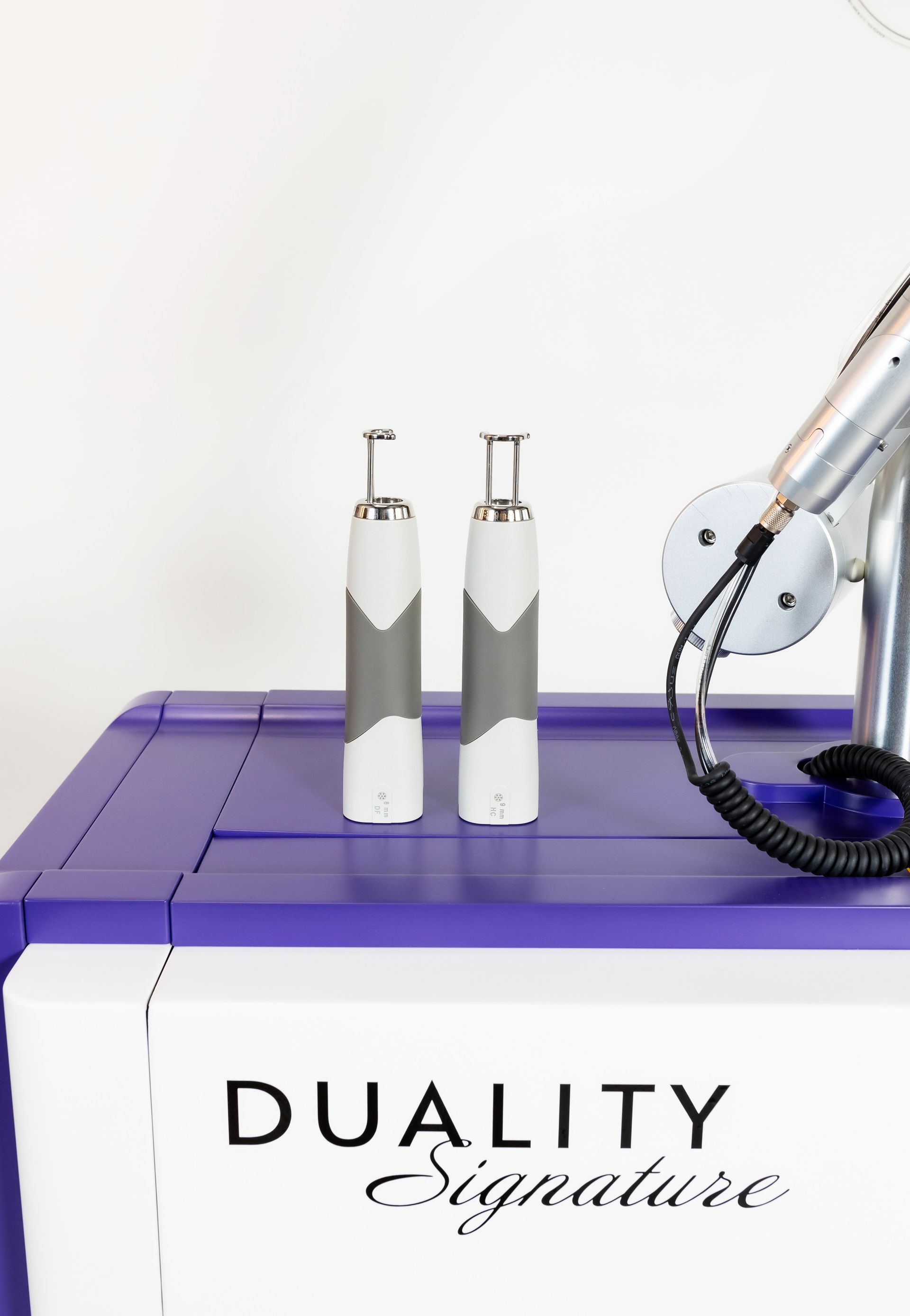 Two white and gray handheld medical devices sit atop a purple and white machine labeled 