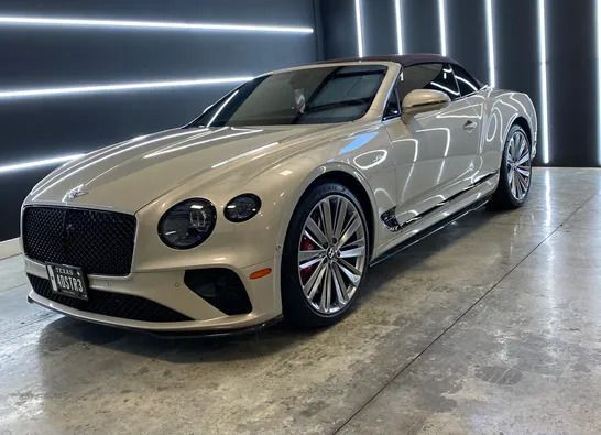 A bentley continental gt convertible is parked in a garage.