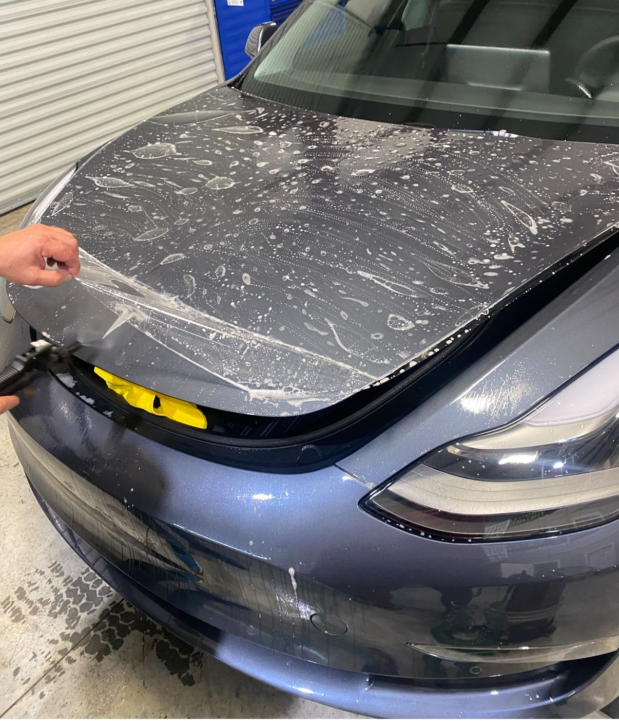 a person is applying a protective film to the hood of a car .