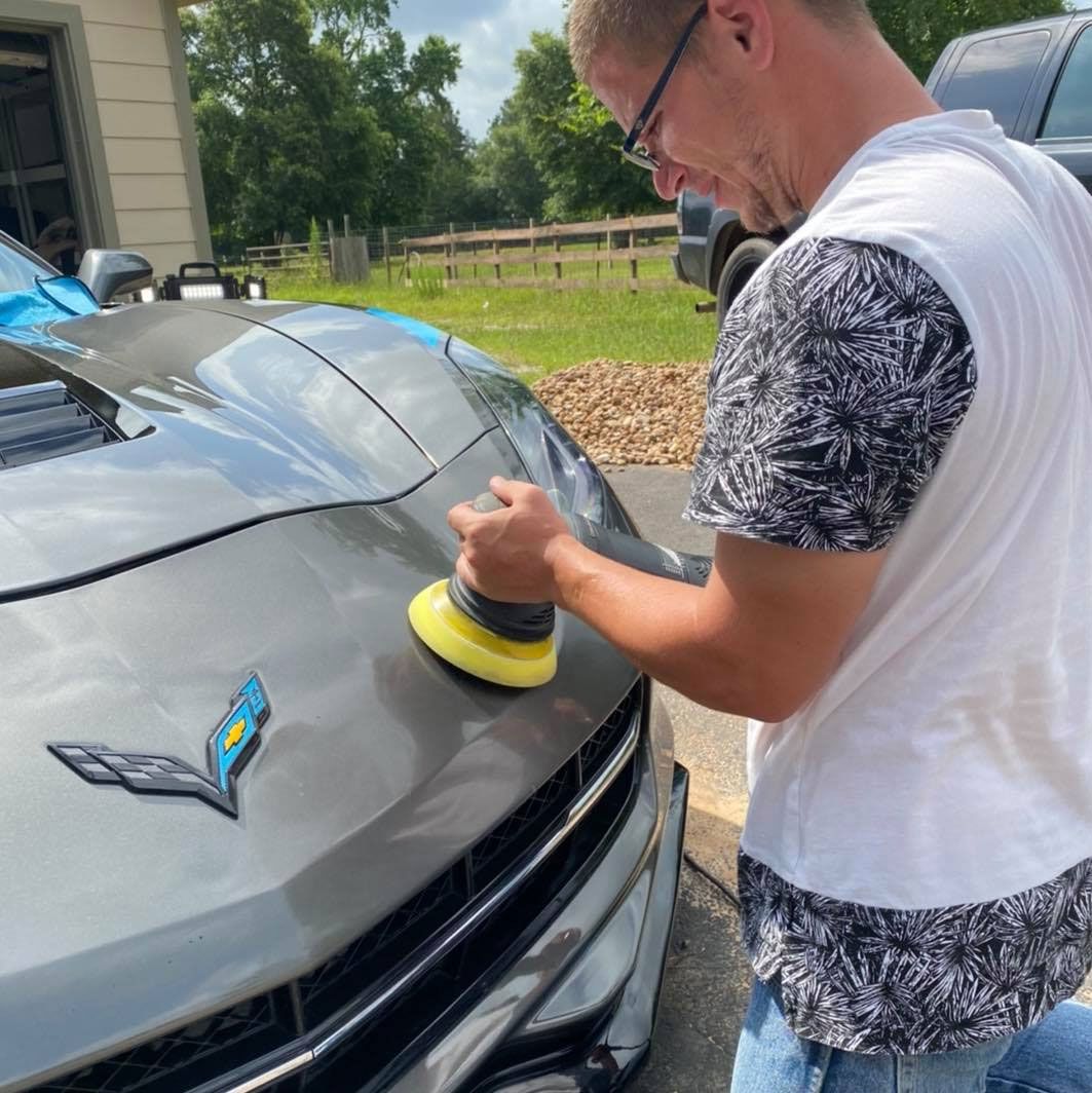 A man is polishing the hood of a car.