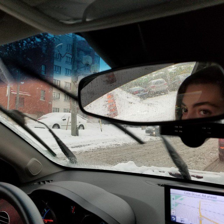 a woman is looking at her reflection in the rear view mirror of a car