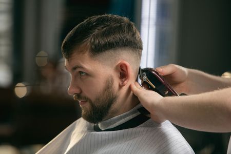 Barber trimming a man’s hair with clippers in a modern salon
