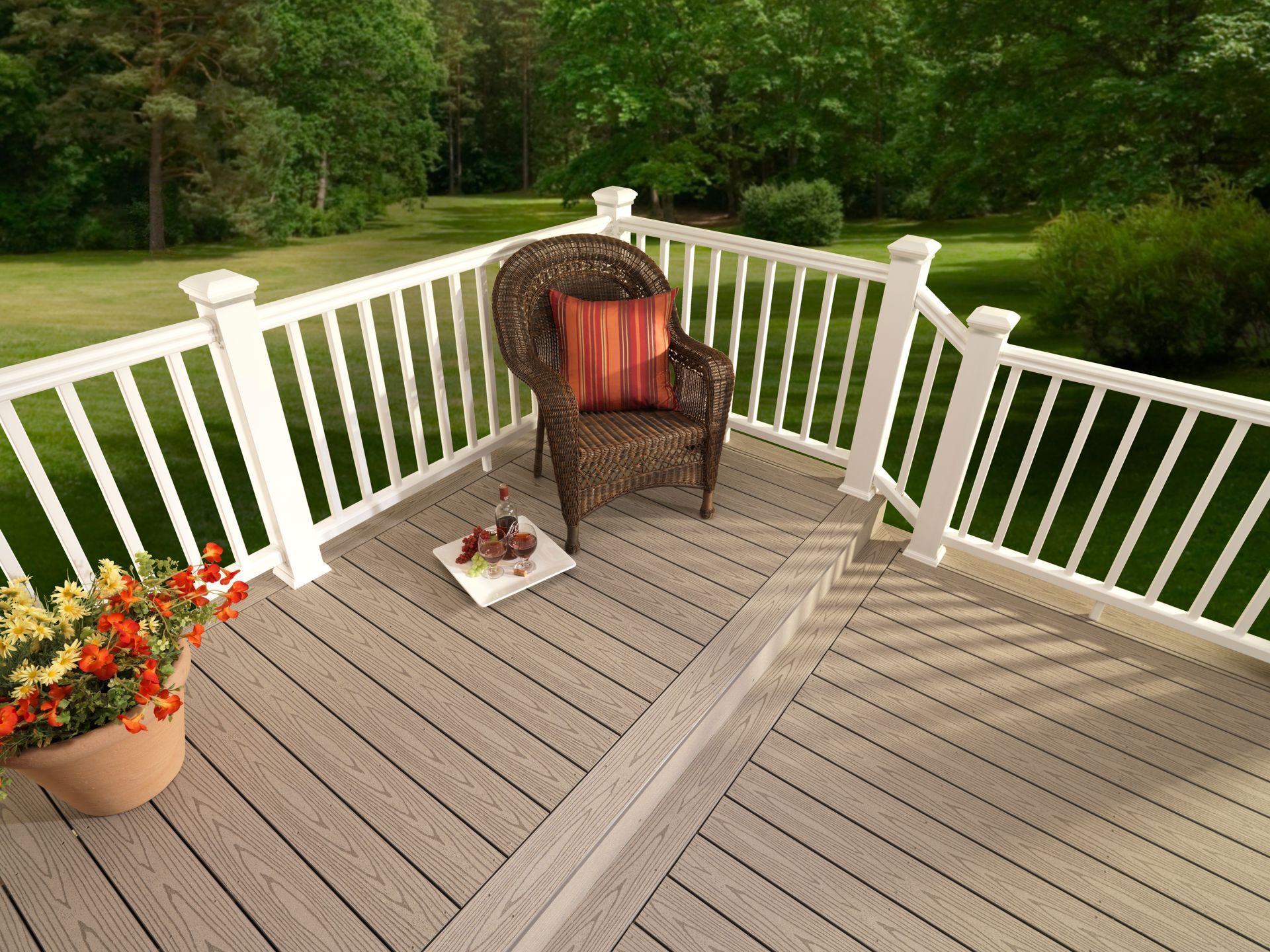 A wicker chair is sitting on a wooden deck with a white railing.