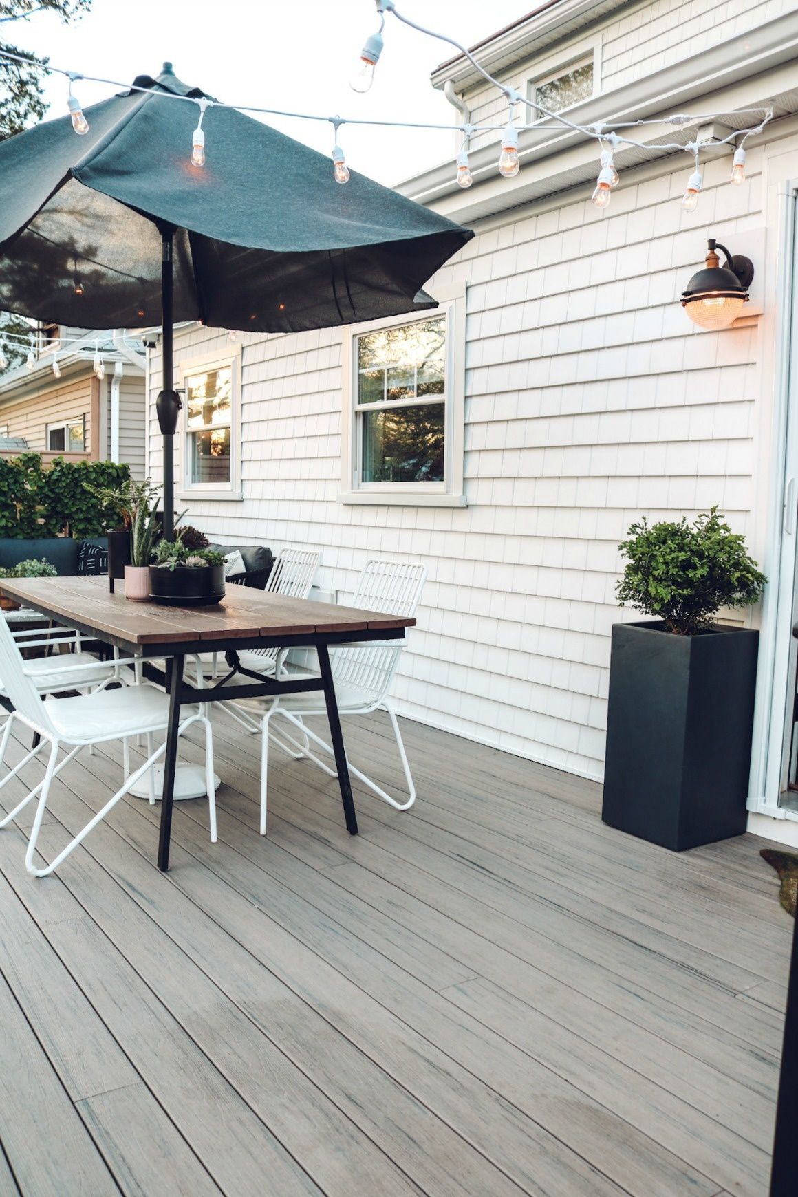 A wooden deck with a table and chairs under an umbrella.