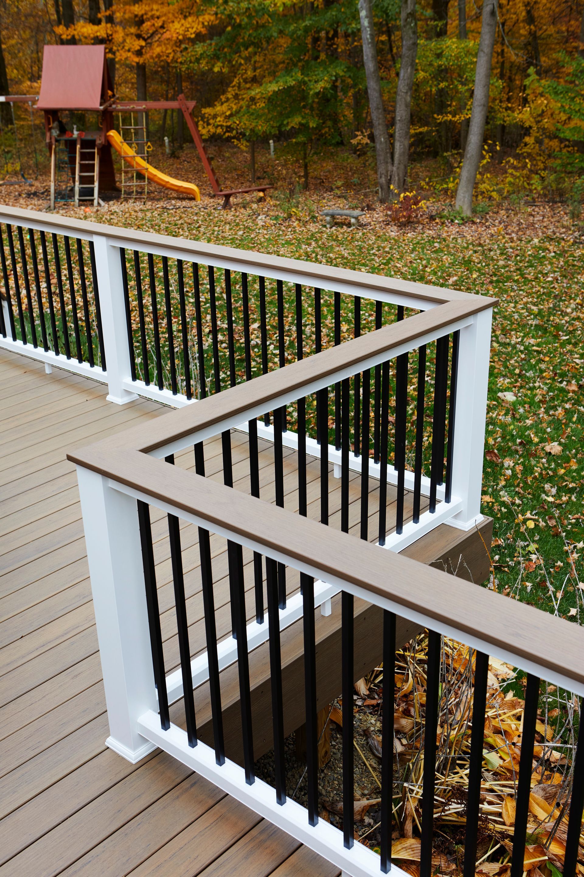 A deck with a black railing and a playground in the background