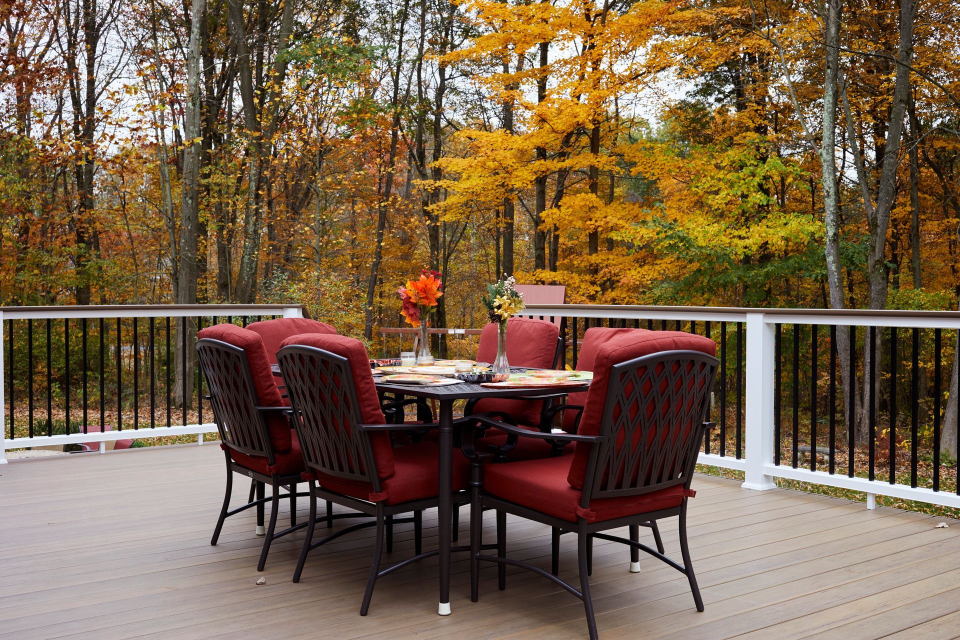 A table and chairs on a deck with trees in the background