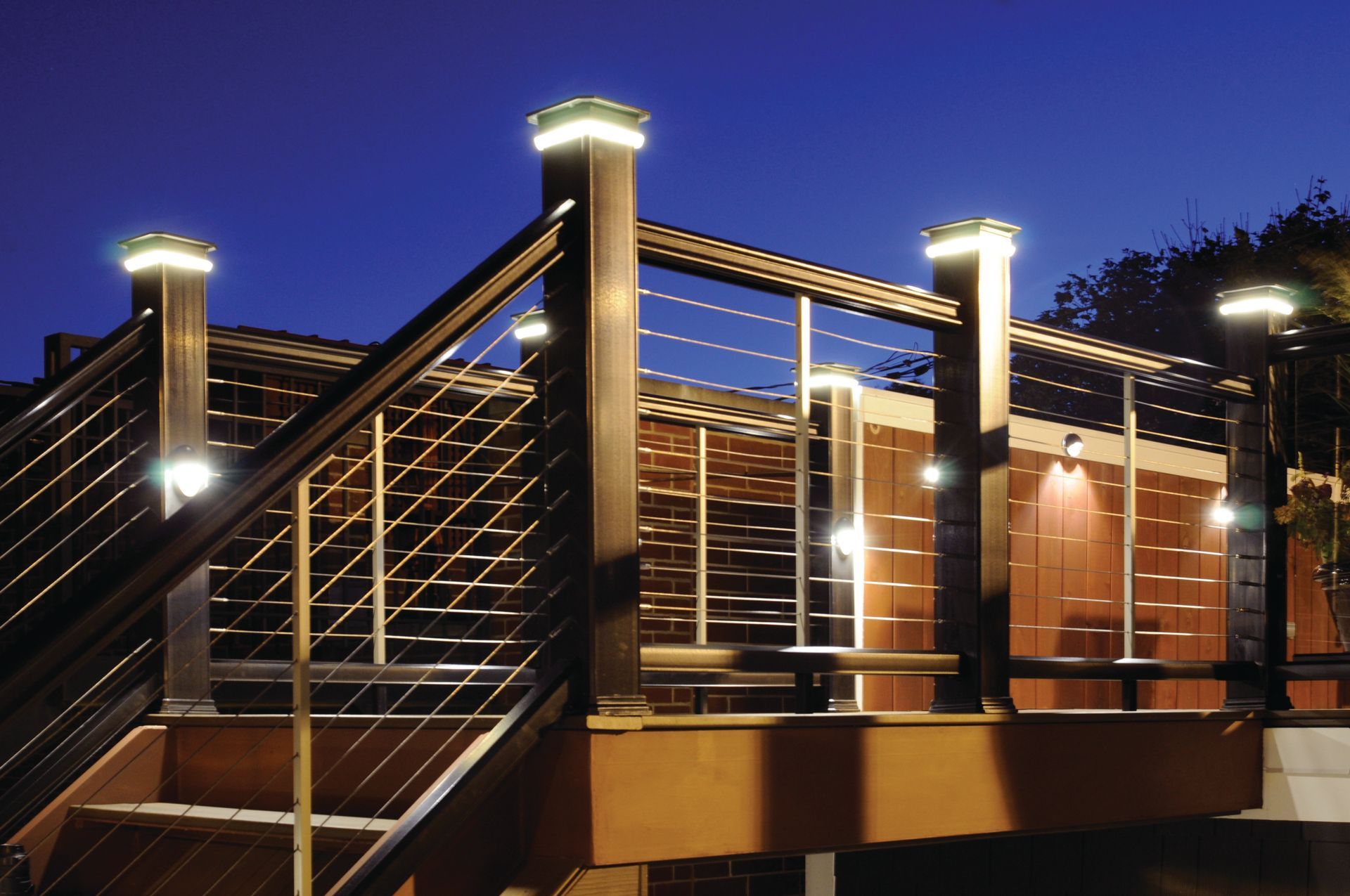 A wooden deck with stairs and lights at night
