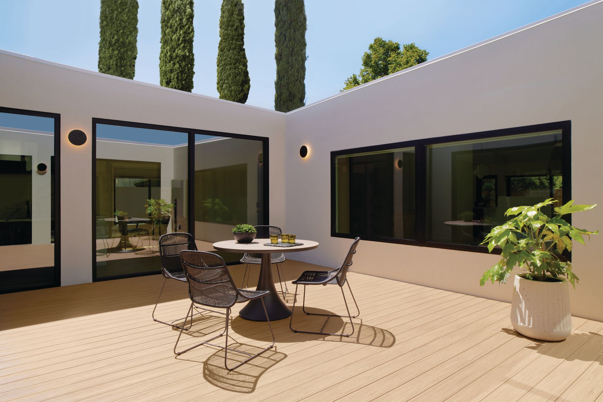 There is a table and chairs on the deck of a house.