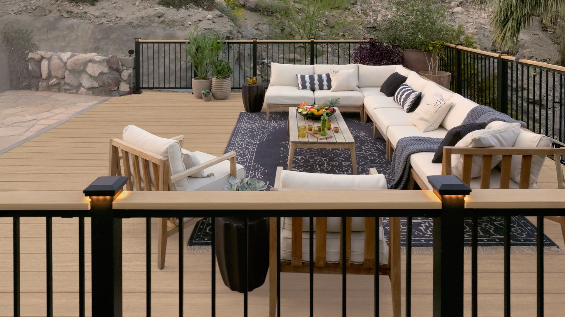 A wooden deck with a couch , chairs , and a coffee table.