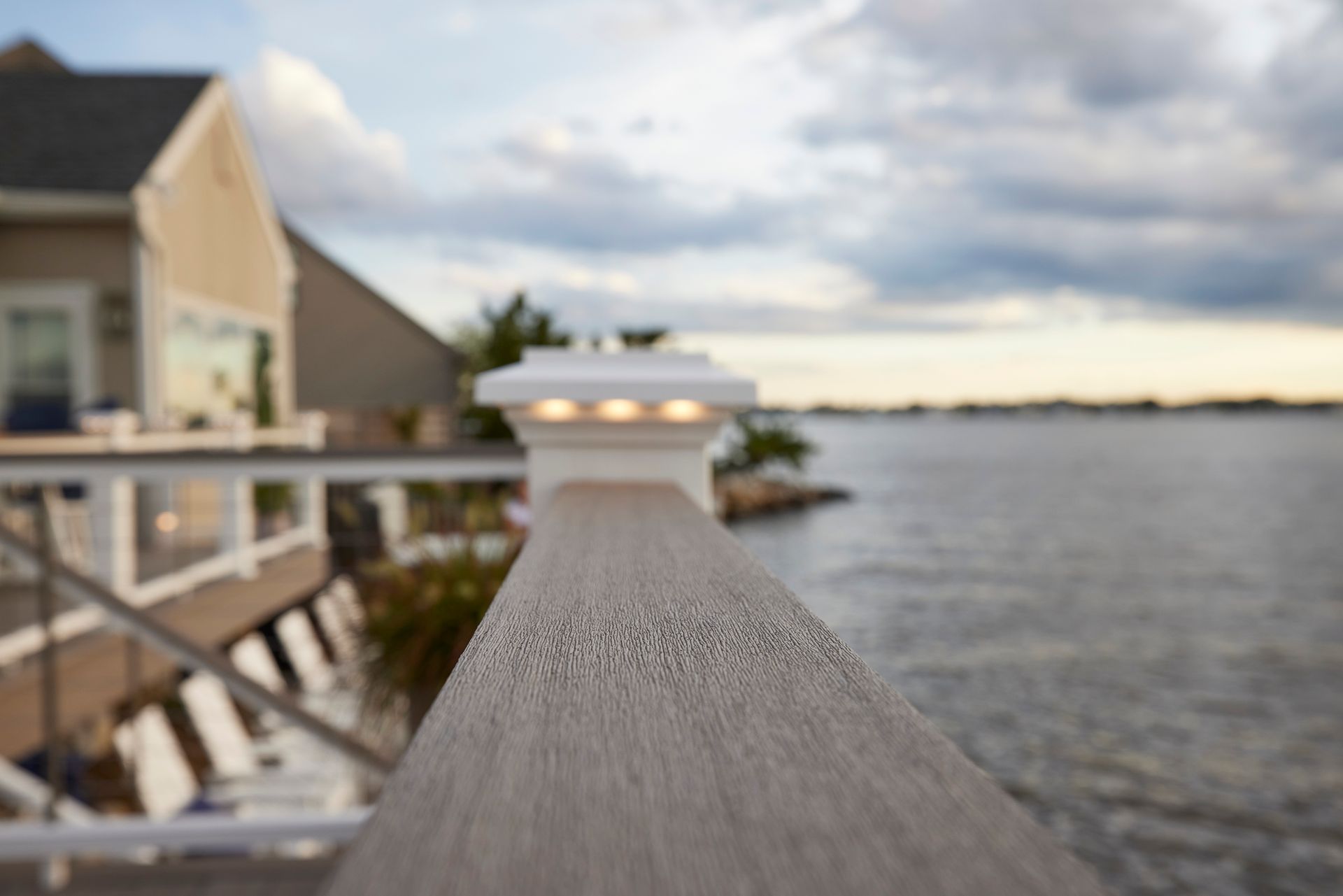 A wooden deck overlooking a body of water with a house in the background.