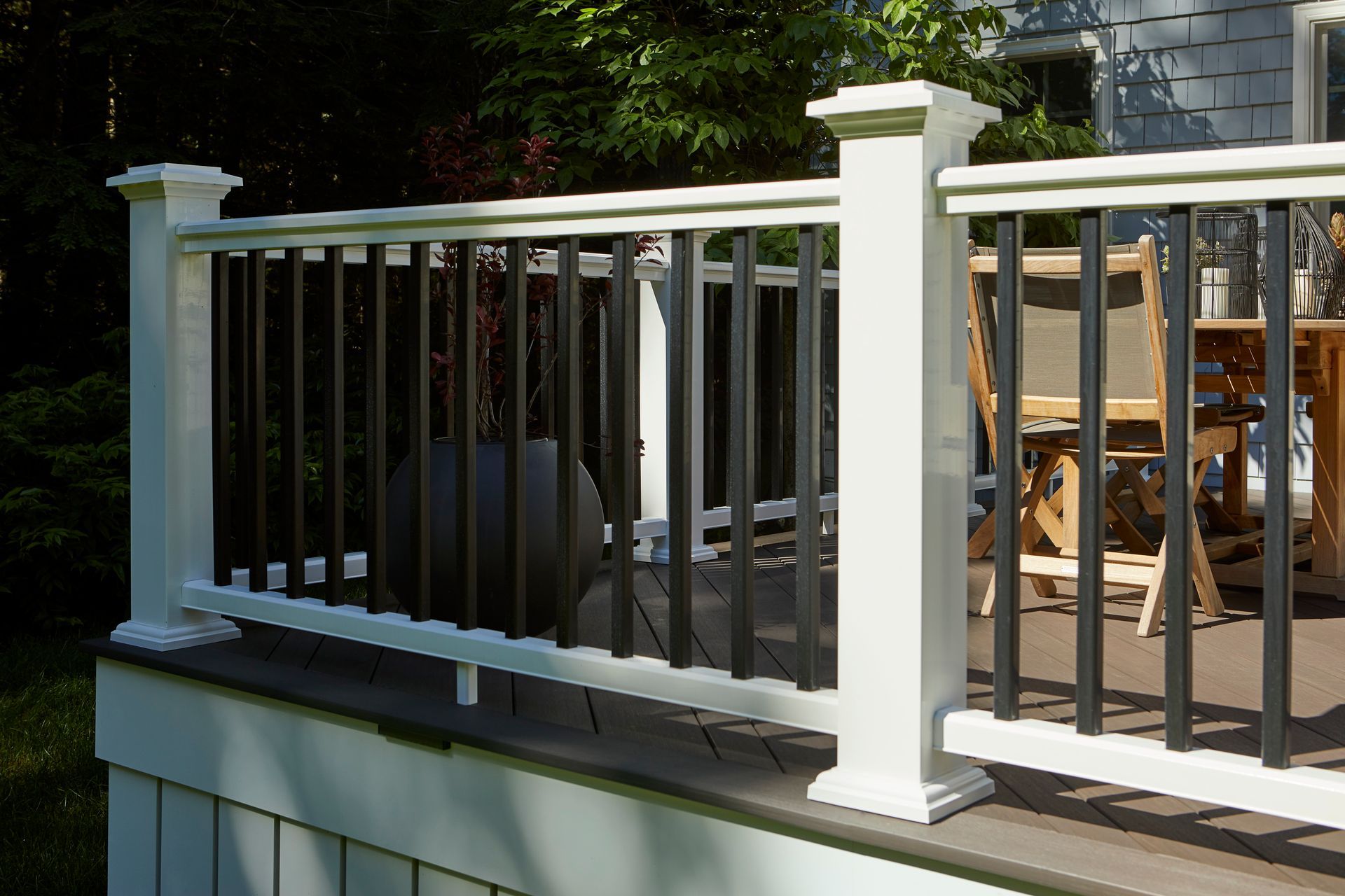 A white and black railing on a deck with a table and chairs.