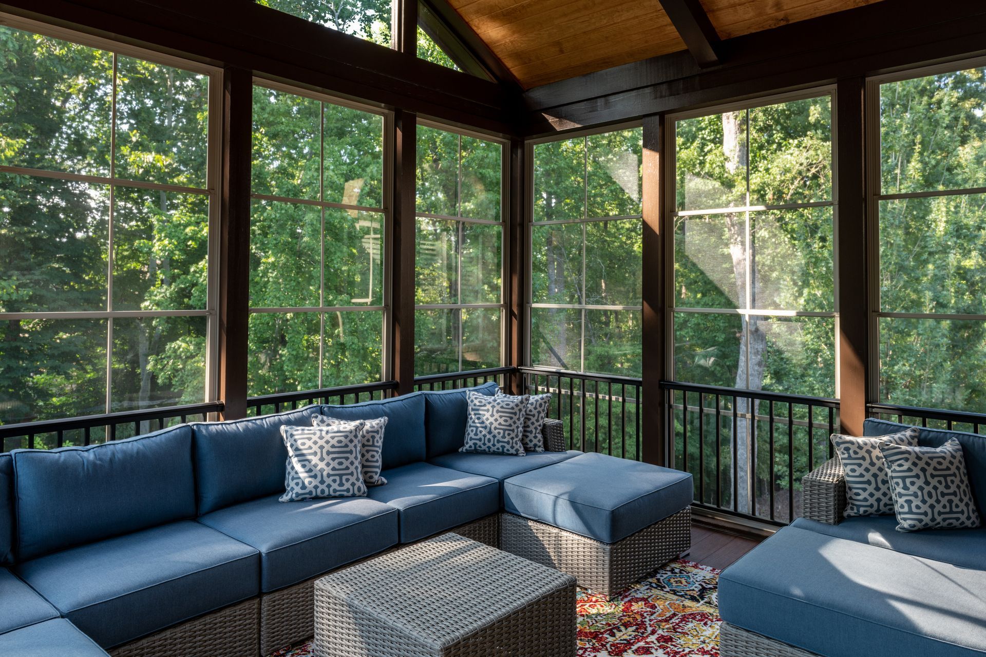 A screened in porch with a lot of windows and blue furniture.