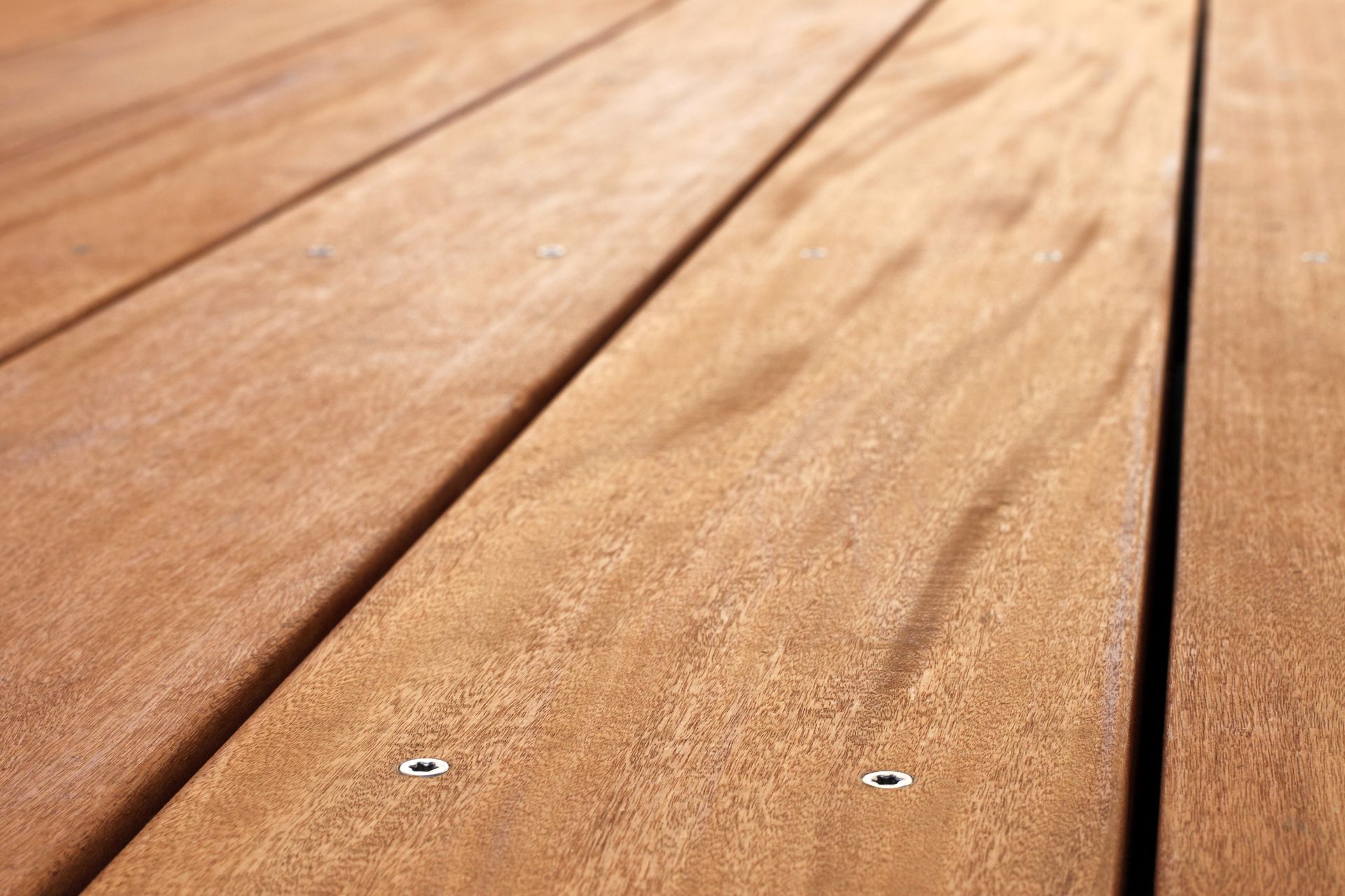 A close up of a wooden deck with screws in it