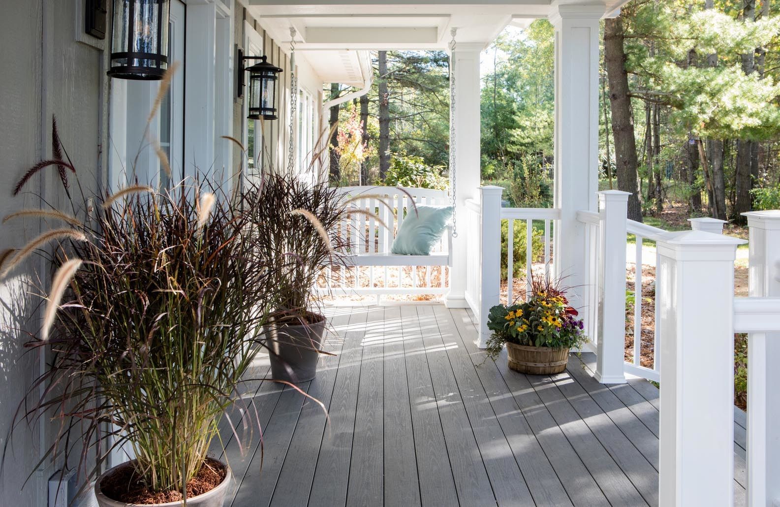 A porch with potted plants and flowers on it.