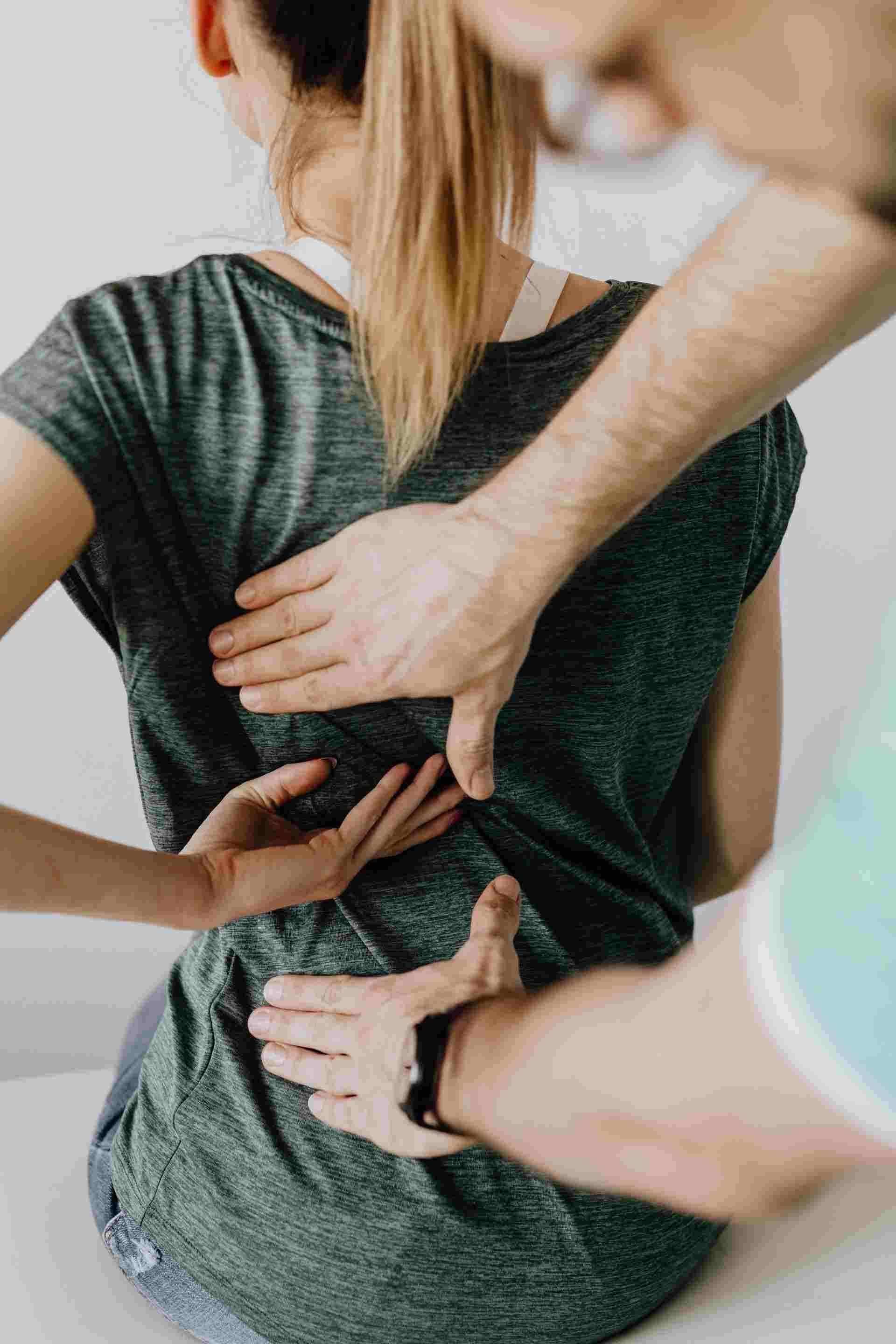 A man massaging a woman's sore back.