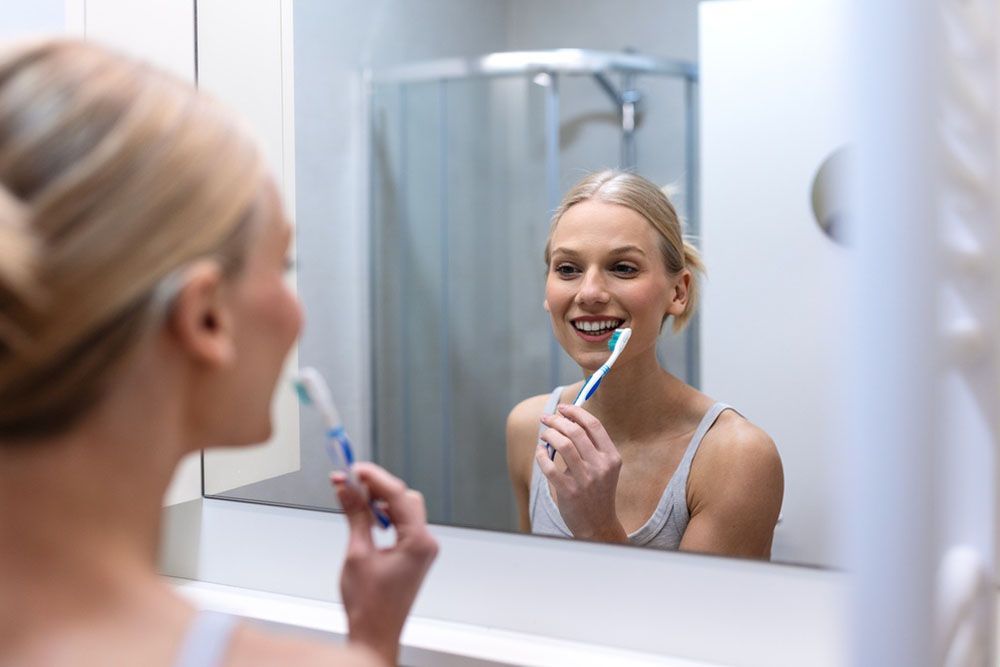 person smiling in front of the mirror (toothbrush in hand)