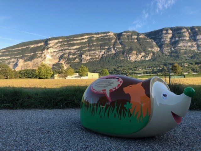 statue de hérisson peinte en brun sur fond montagneux