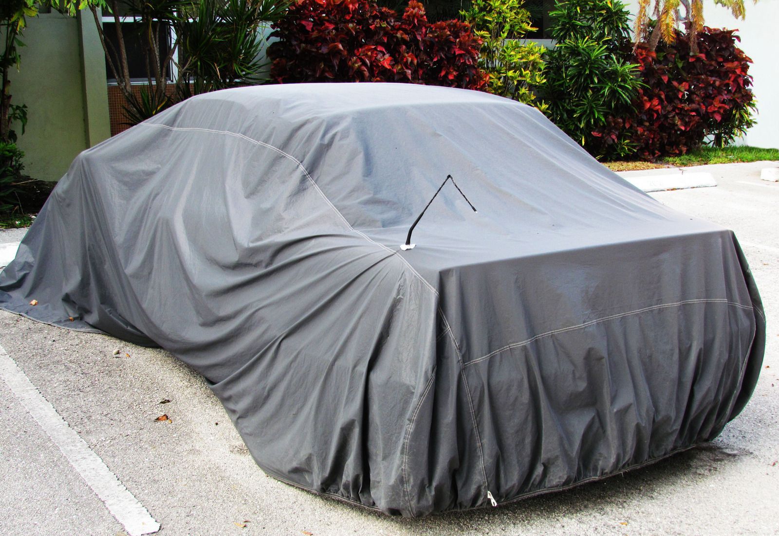 Gray car cover on a vehicle in an outdoor parking area.