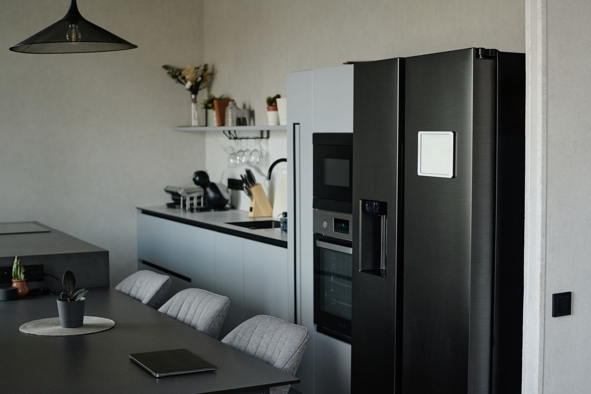 Modern kitchen with a black refrigerator, built-in oven, and a dining table with chairs.
