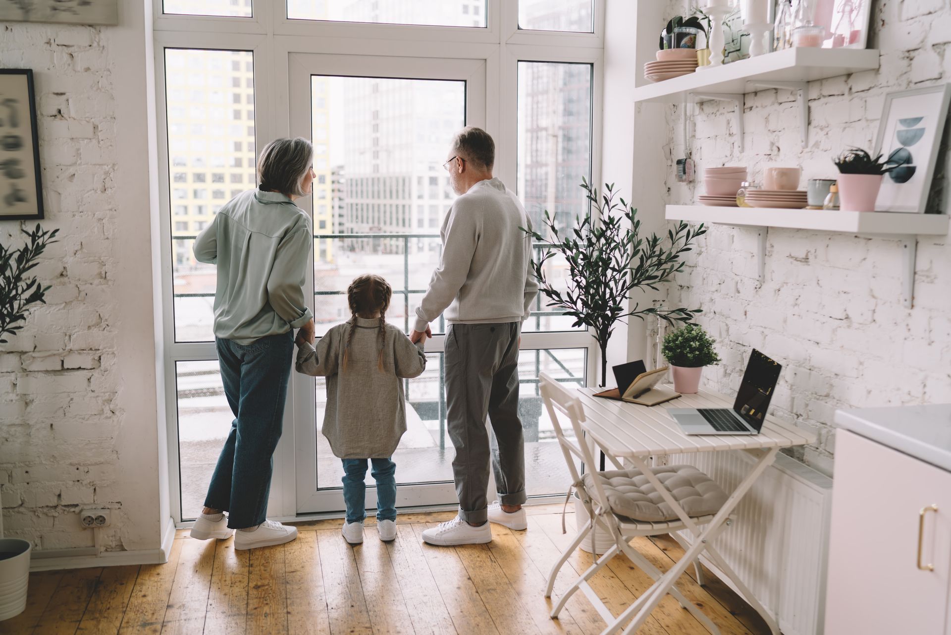Two men and a child looking out a window in a bright, modern room.