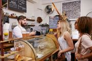 A barista taking an order from two customers at a cafe counter.