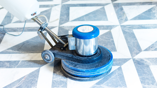 A machine is cleaning a marble floor with a pattern.