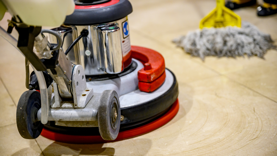 A person is using a machine to clean a wooden floor.