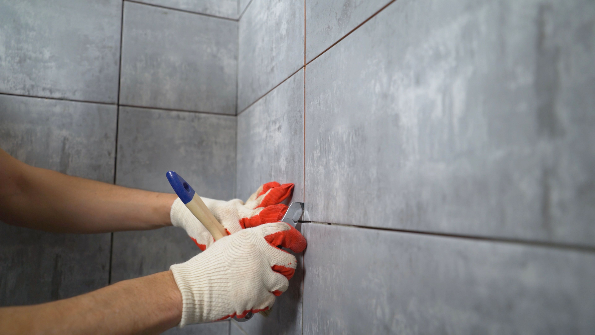 A man is installing tiles on a wall in a bathroom.