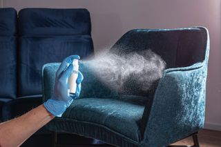 A person is spraying a chair with a spray bottle.