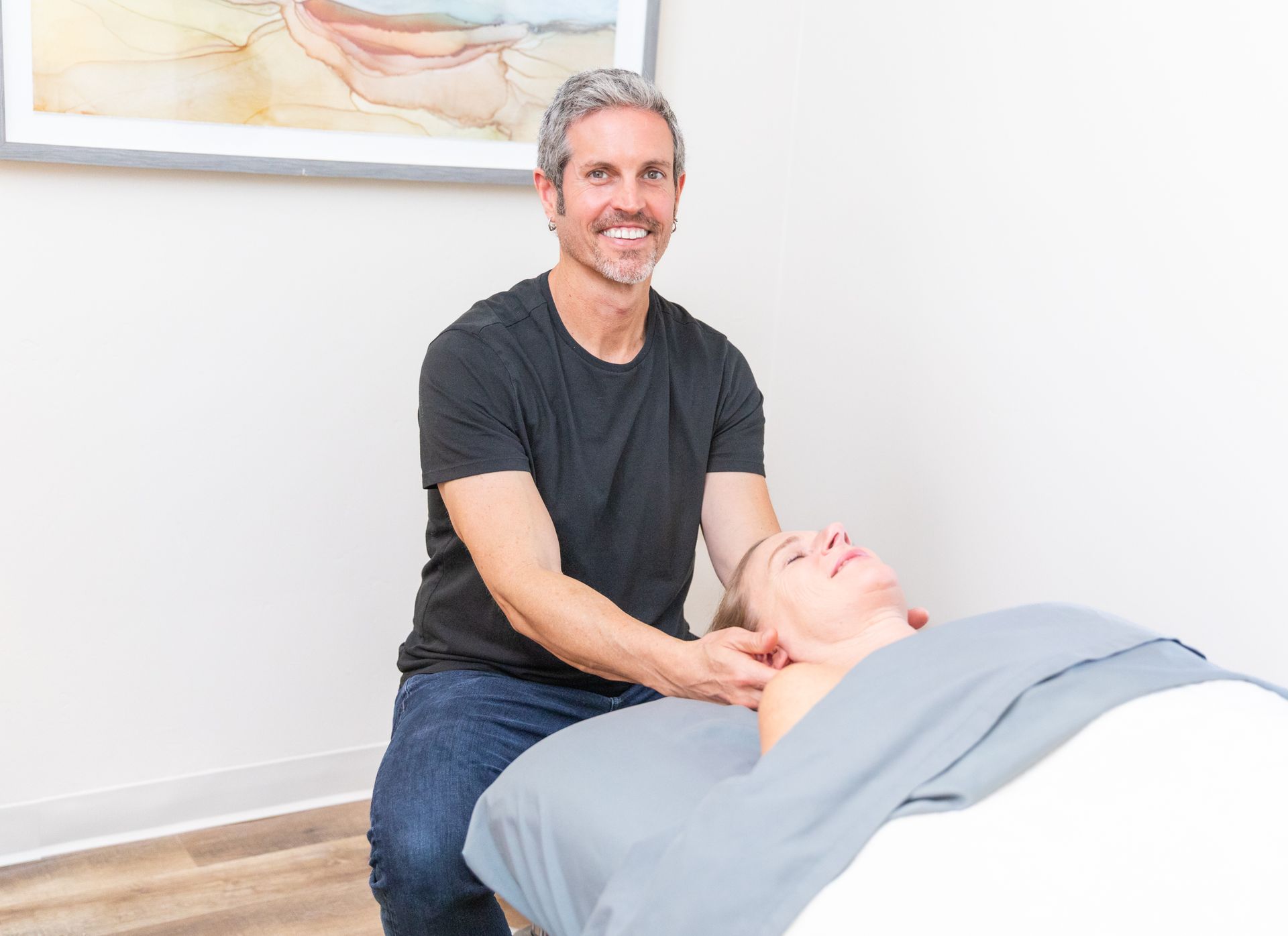 Massage therapist working on a patient's neck in a treatment room.