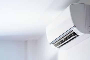 A white air conditioner mounted on a white wall in a room.