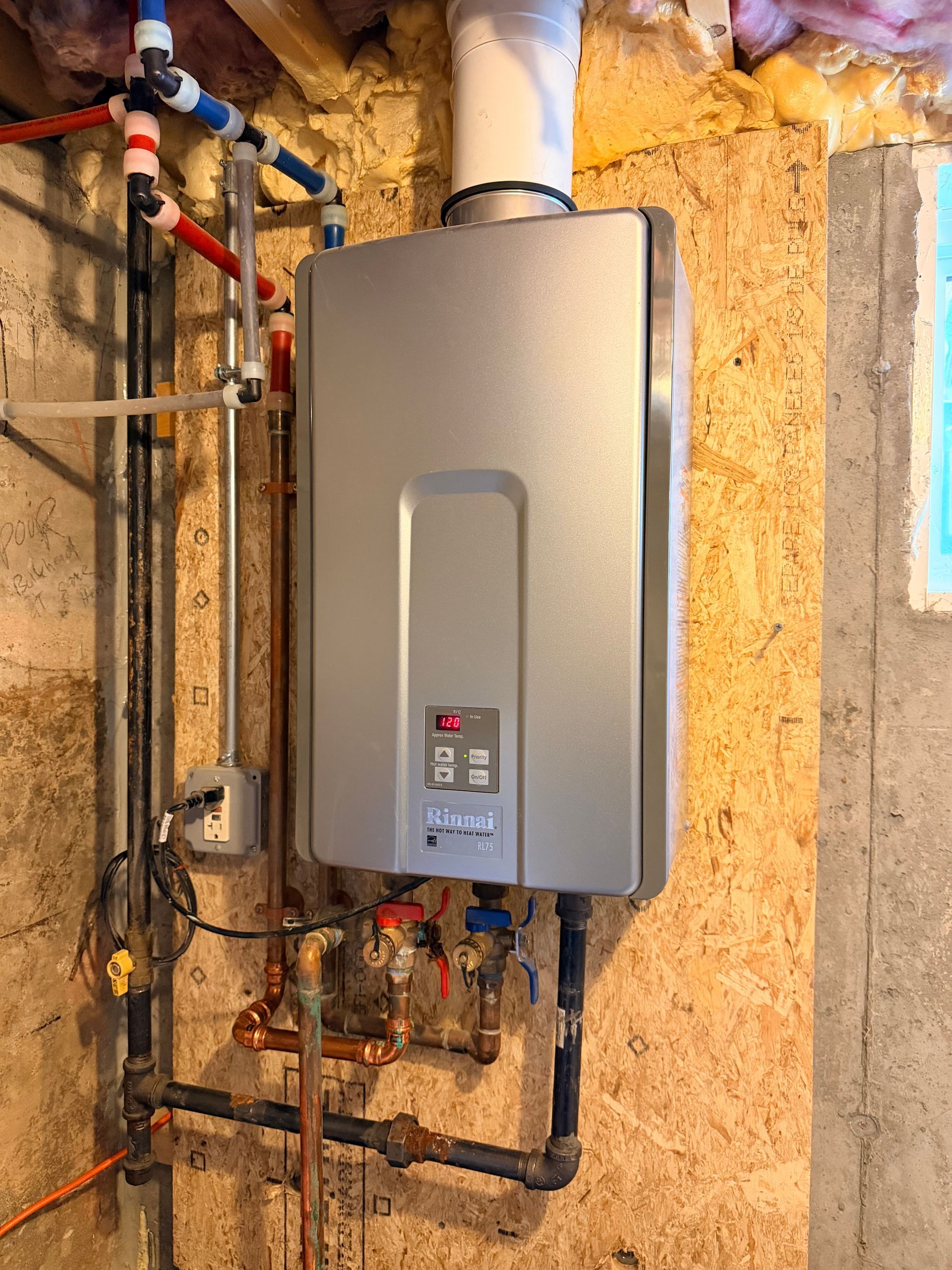 Technician in blue overalls inspecting a boiler, taking notes on a clipboard.