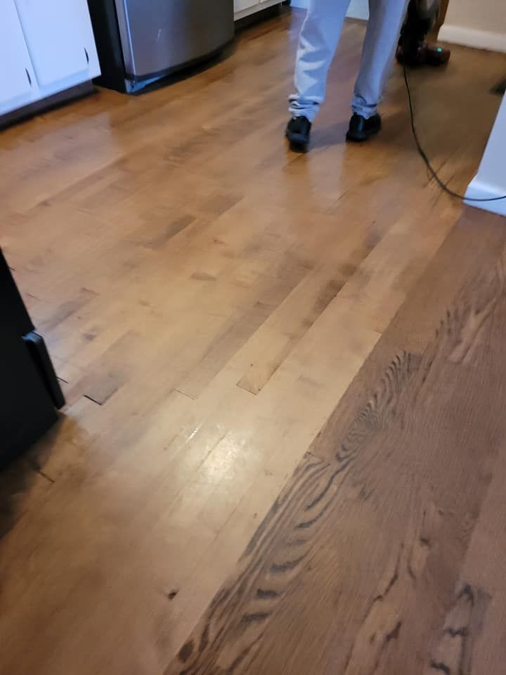 Person standing on a hardwood floor, part light and dark wood.