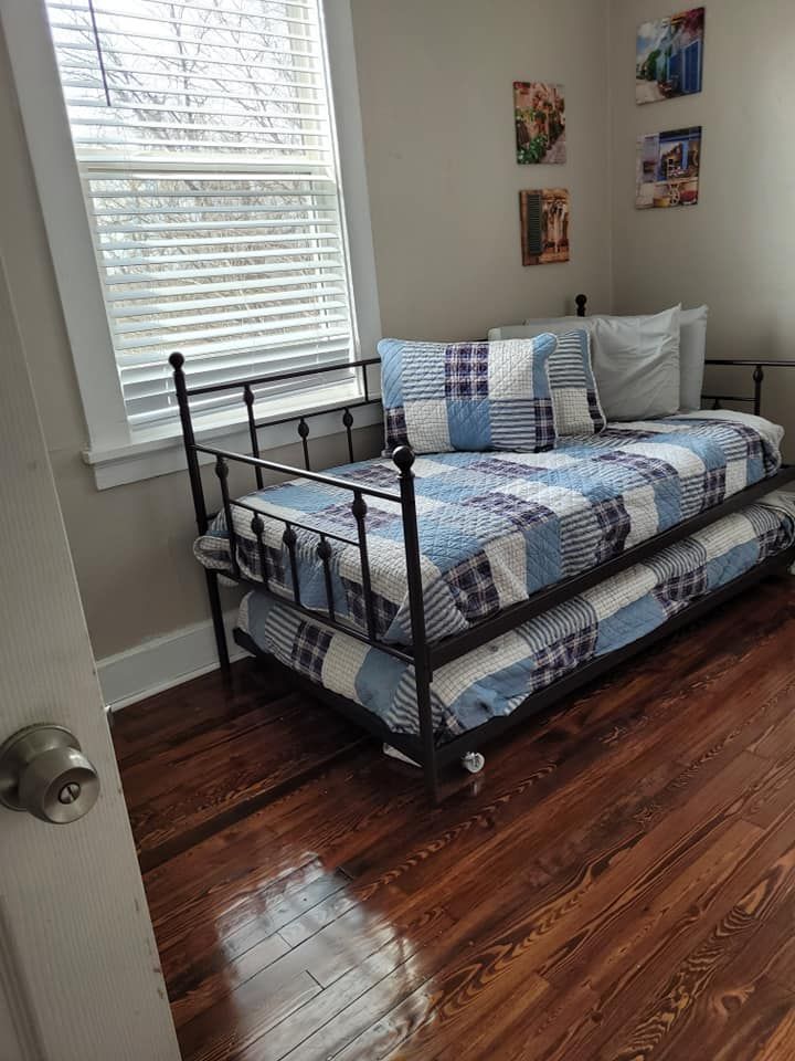 Black metal daybed with a trundle in a room with hardwood floors and a window.