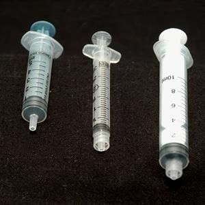 Three syringes of different sizes are lined up on a black surface