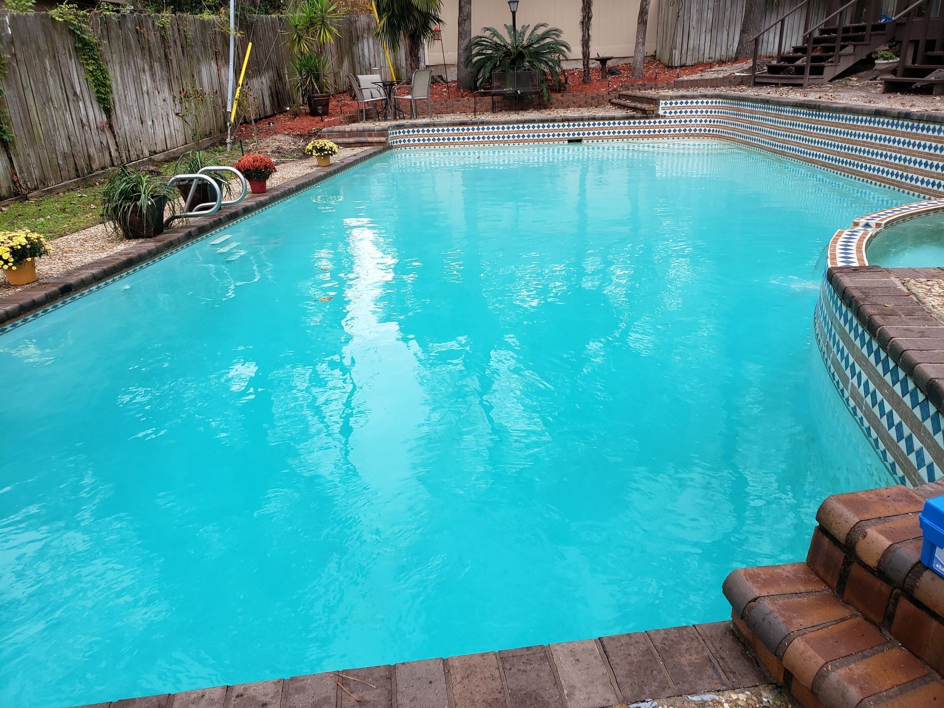 A large swimming pool with a hot tub in the backyard.