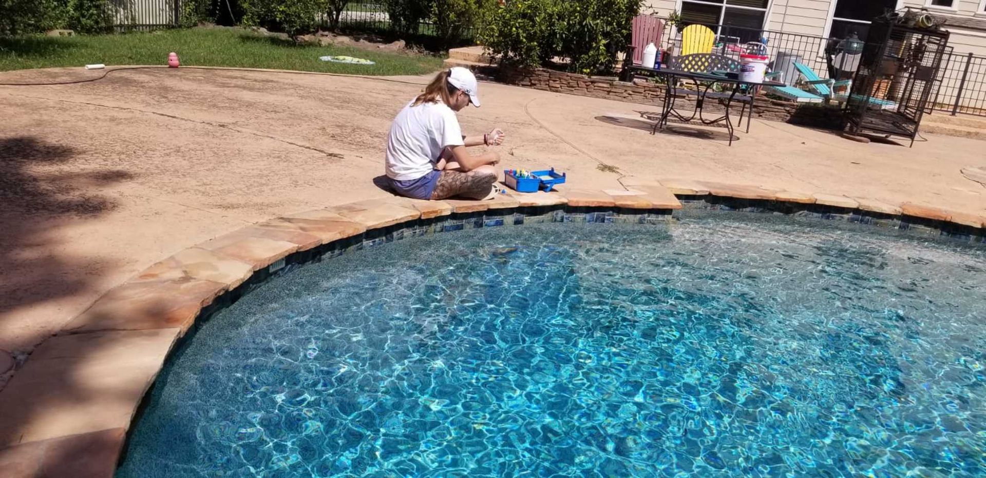 A woman is sitting on the edge of a swimming pool.