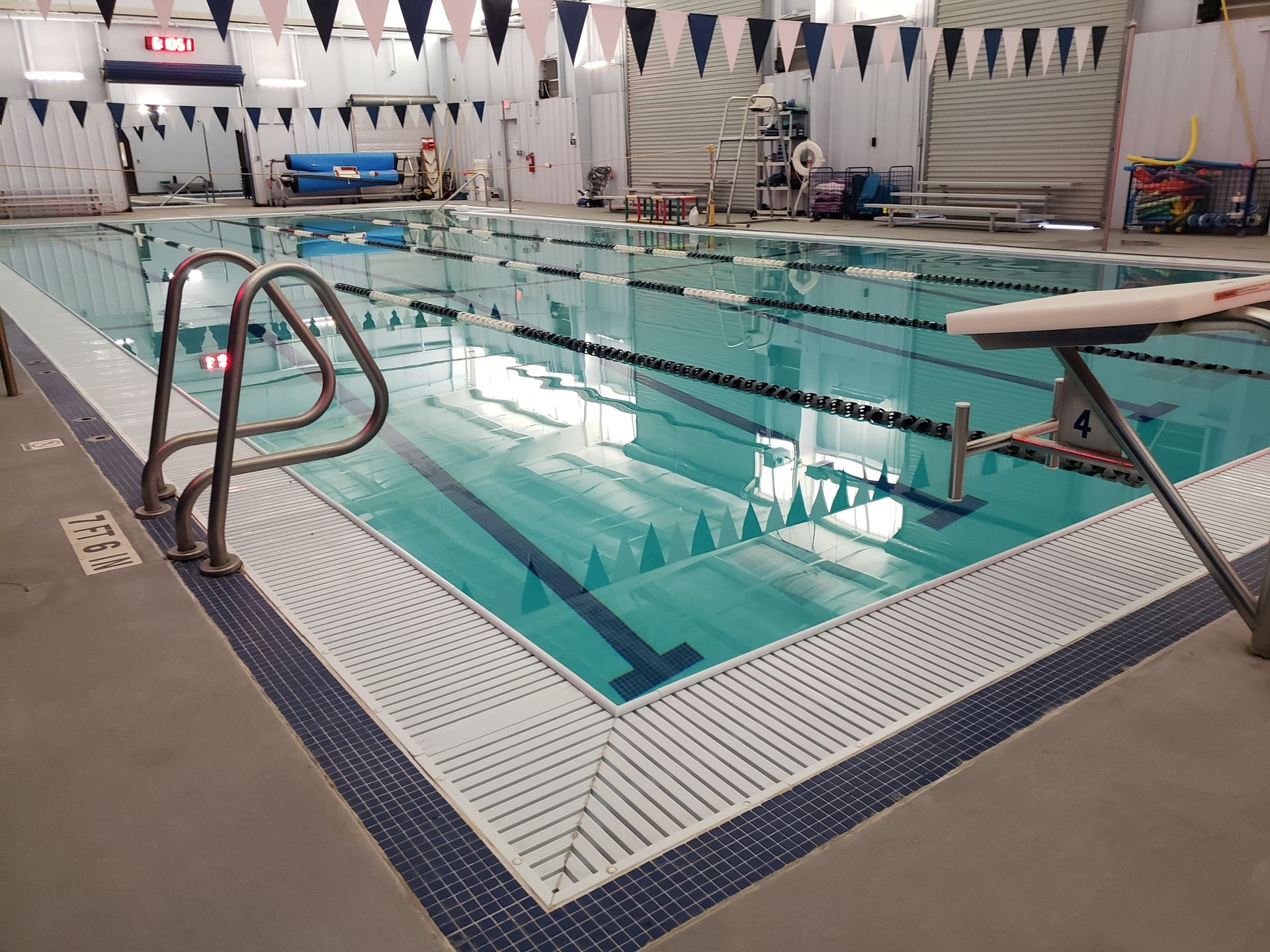 A large indoor swimming pool with a ladder and a starting block.