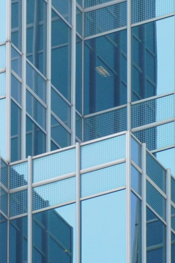 Blue glass skyscraper facade with silver metal framing and reflective windows