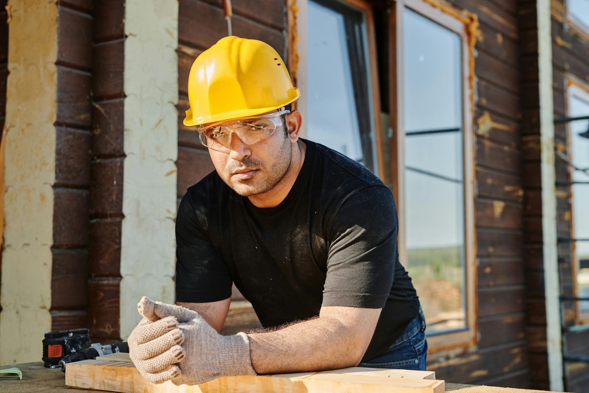 Construction worker in yellow hard hat leaning on a beam at a building site