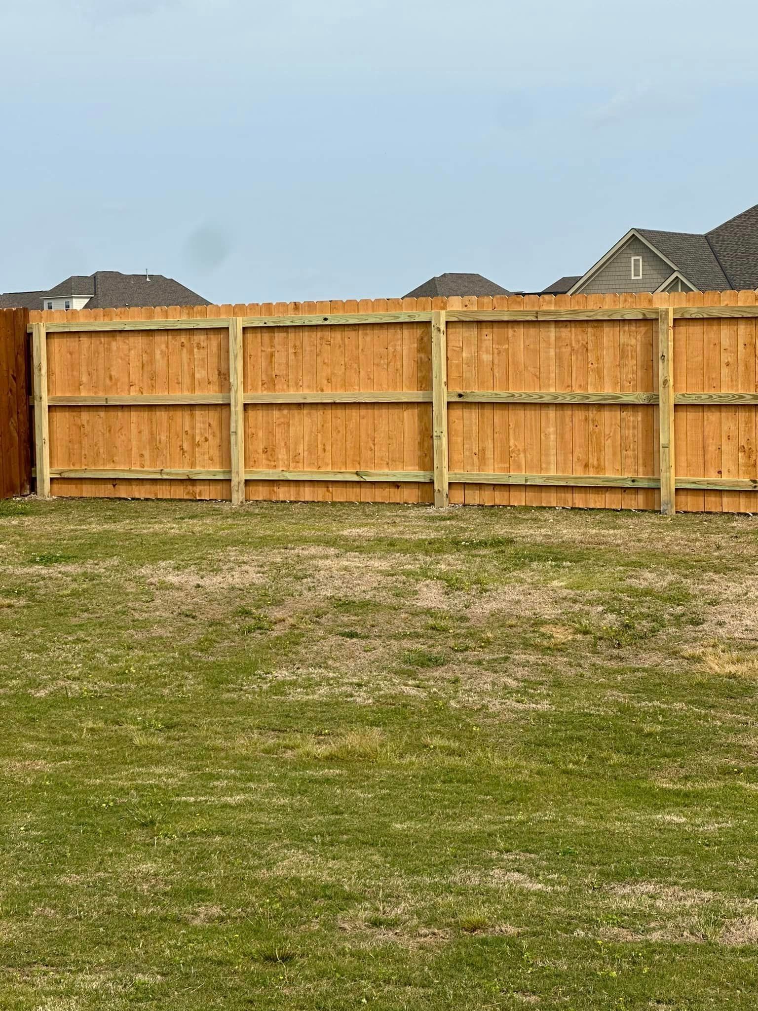 A wooden fence is sitting on top of a lush green field.