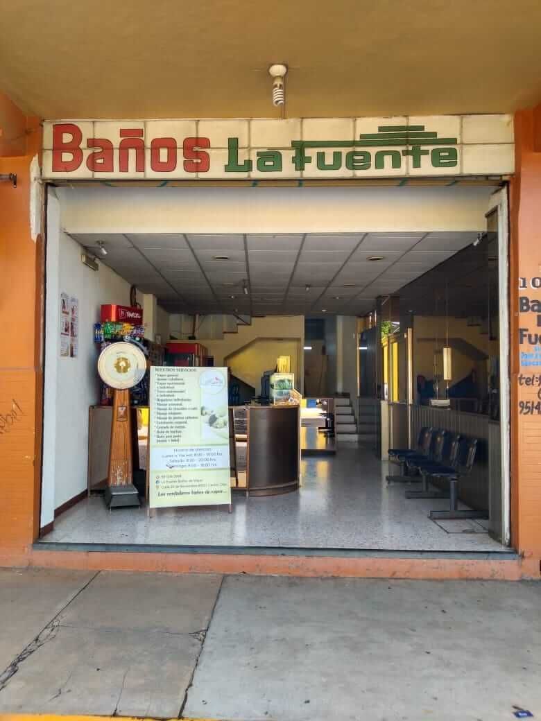 Un frente de tienda con un cartel que dice baños la fuente