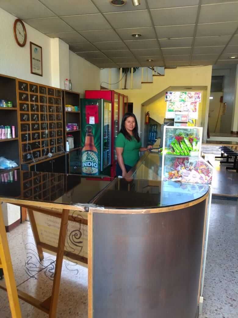 Una mujer con una camisa verde está parada en un mostrador en una tienda.