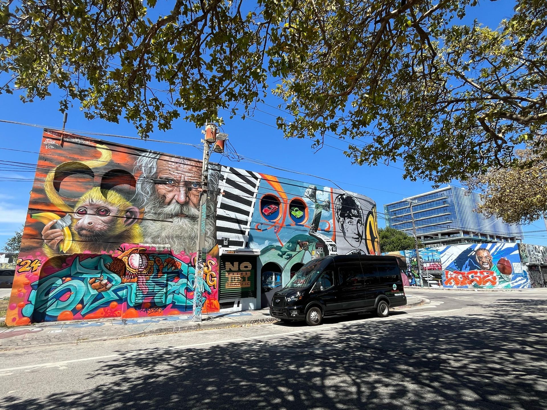 Hop-On Hop-Off Miami Tour Bus parked at Wynwood Walls with colorful murals in the background

