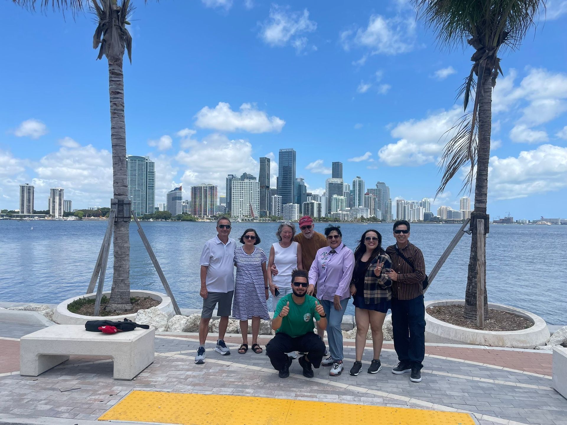 Tour guide on a hop on hop off City tour taking photos with Passengers with the Miami Skyline in the background 