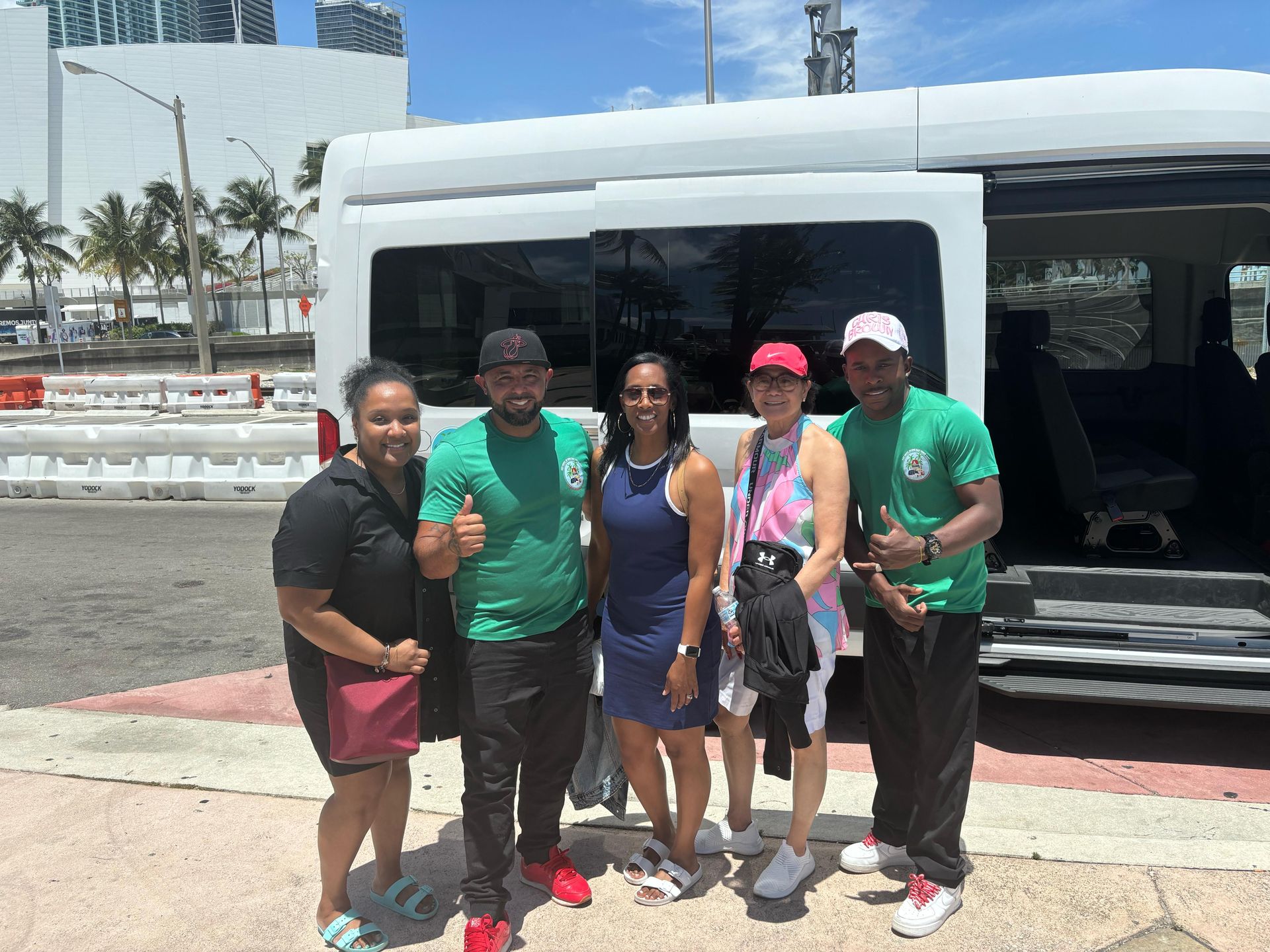 Happy tourists posing with tour guides next to the Best Miami Tours Bus near Downtown Miami after a fun sightseeing adventure.
