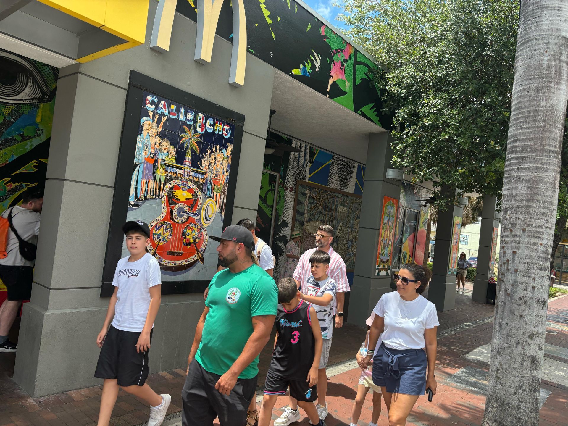 Guests on the Miami sightseeing bus tour walking past the iconic Calle Ocho mural during a stop in Little Havana on the Miami City Bus Tour.
