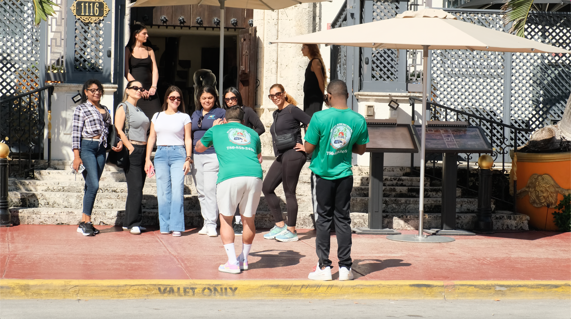 Tour group taking photos in front of the iconic Versace Mansion on Ocean Drive
