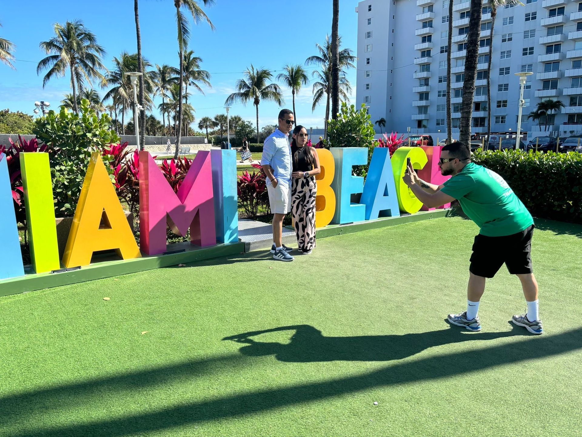 Tour guide taking photos under the Miami Sun in the Miami Beach sign in Ocean drive